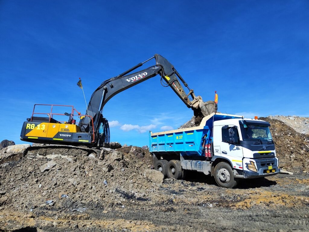Excavadora cargando material en un camión de volteo durante un movimiento de tierra