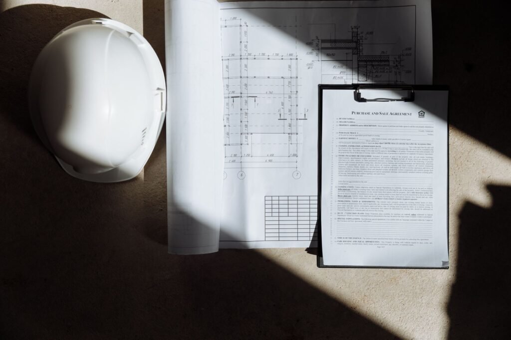 Documentos de obra y casco de seguridad vistos desde arriba sobre una mesa
