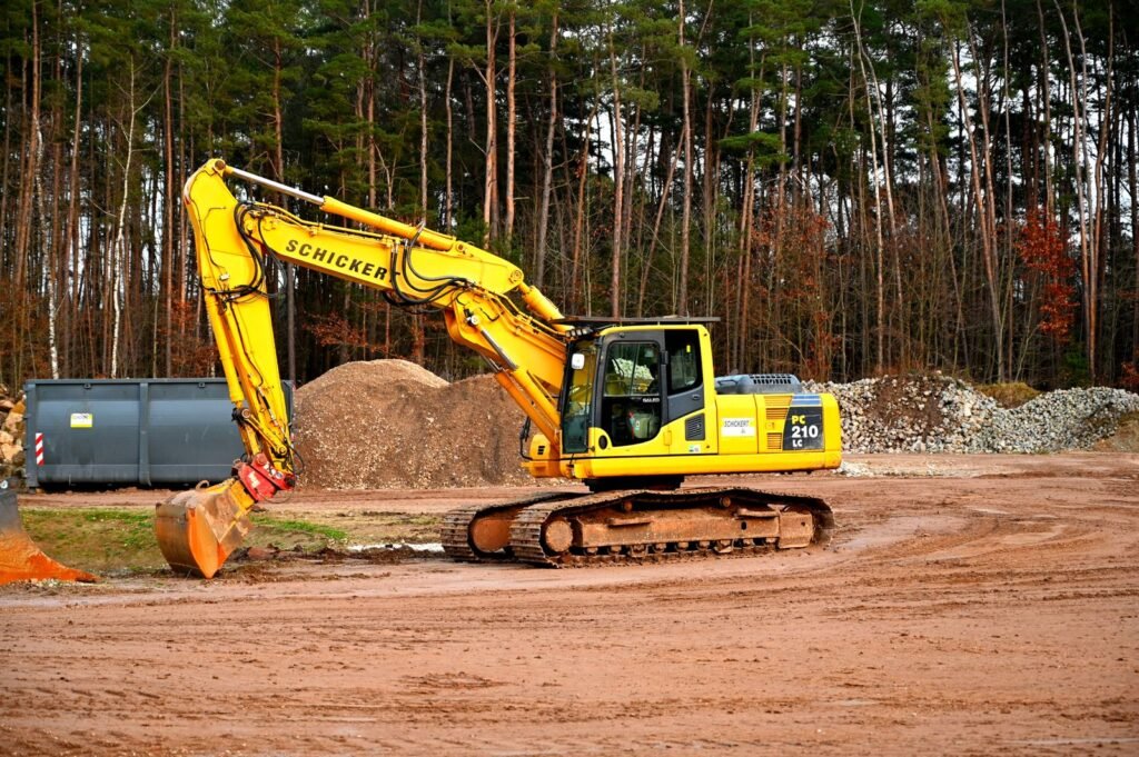 Excavadora de orugas amarilla trabajando sobre terreno de tierra roja