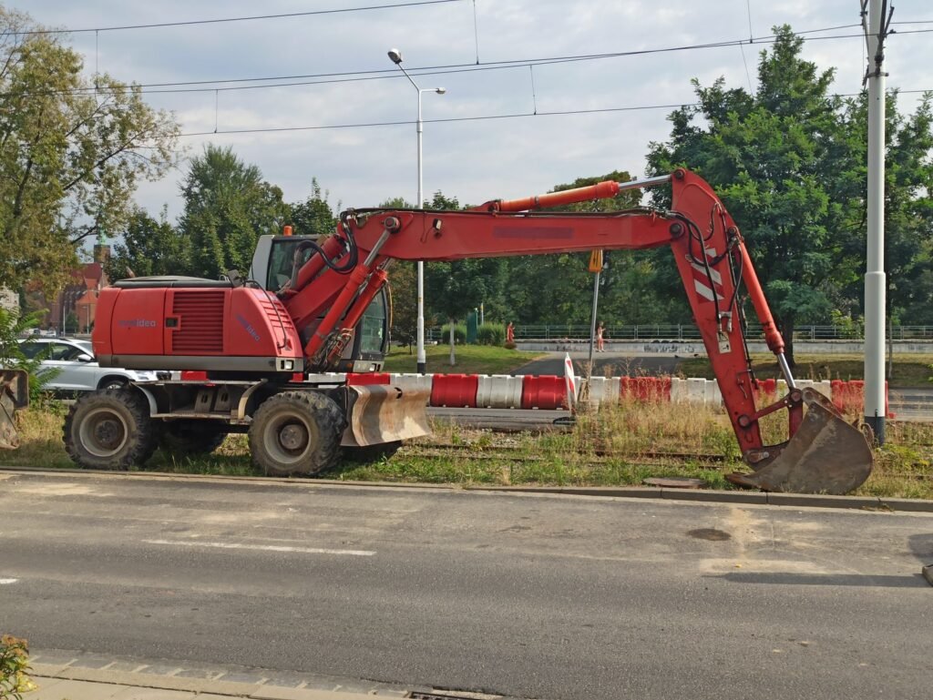 Excavadora de ruedas trabajando a un costado de una calle urbana