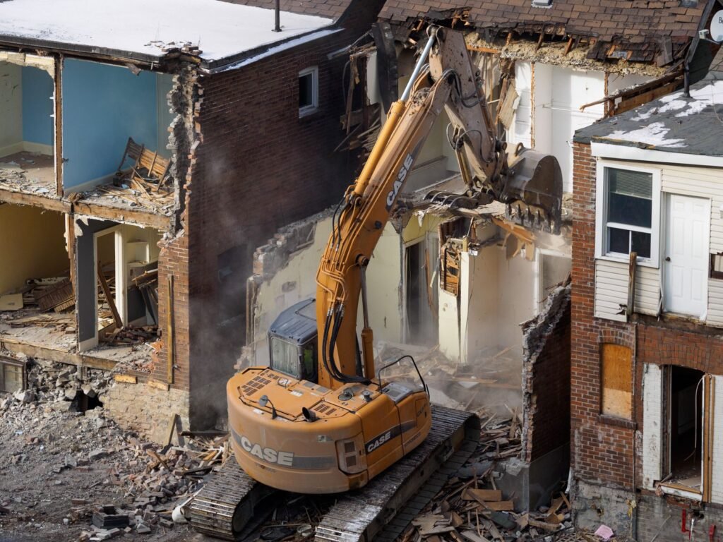 Excavadora demoliendo una construcción antigua entre escombros