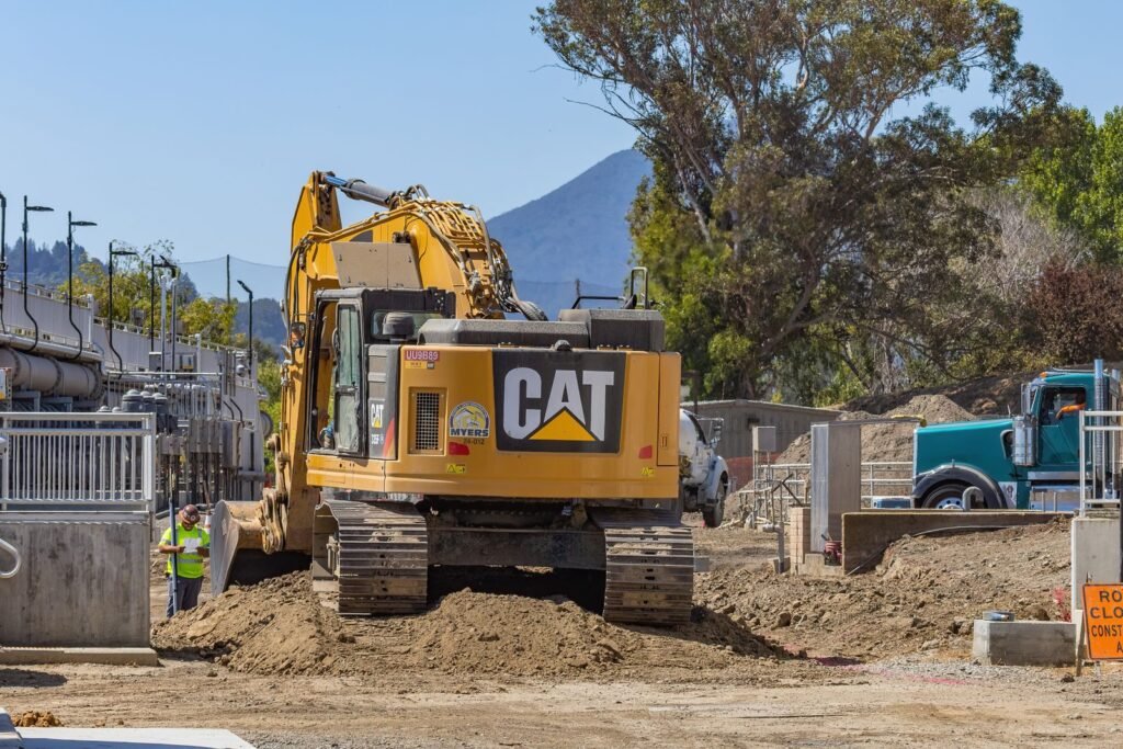 Excavadora de orugas trabajando en una obra junto a montones de tierra