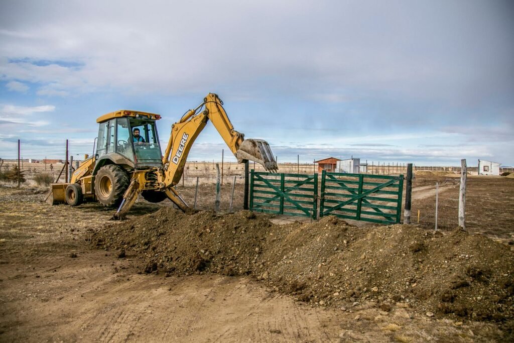 Retroexcavadora excavando tierra con la retro mientras apoya los estabilizadores