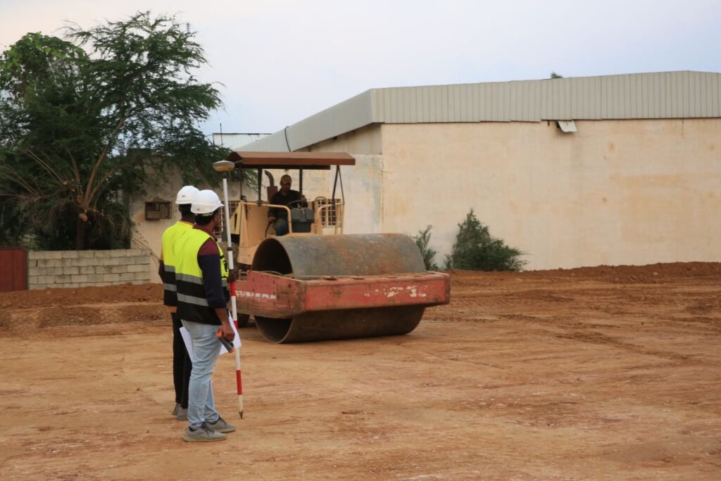 Trabajadores revisando la compactación de un terreno junto a un vibrocompactador