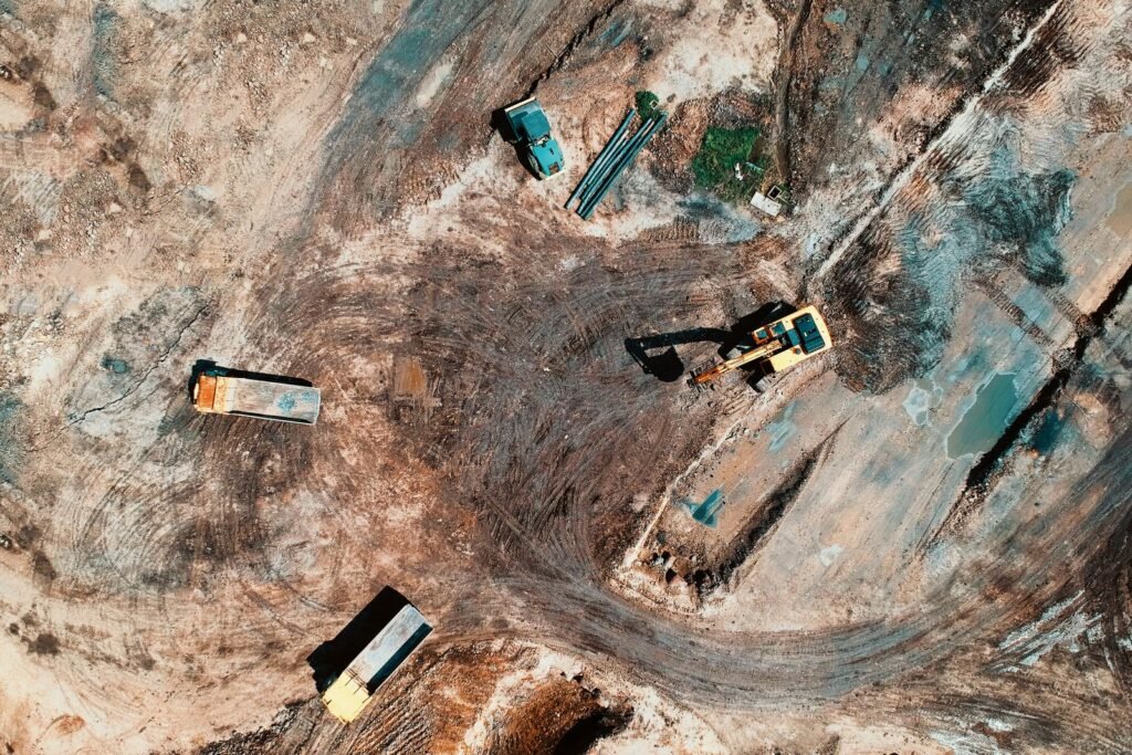 Vista aérea de una obra de movimiento de tierra con excavadora y camiones